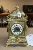 A 20TH CENTURY BRASS MANTEL CLOCK, the heavily cast case with urn shaped finial on domed top, the