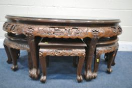 AN ORIENTAL CARVED OVAL COFFEE TABLE, with a sit on glass top, along with six smaller tables