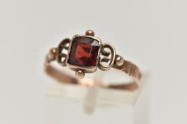 AN EARLY VICTORIAN YELLOW METAL GARNET RING, designed with a square cut garnet, collet set,