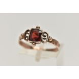 AN EARLY VICTORIAN YELLOW METAL GARNET RING, designed with a square cut garnet, collet set,