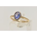 A 9CT GOLD GEM CLUSTER RING, designed as a central oval tanzanite within a circular cut colourless