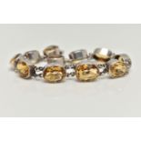 A WHITE METAL CITRINE LINE BRACELET, designed as a series of slightly graduated, oval cut