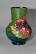 A MOORCROFT POTTERY SQUAT BALUSTER VASE DECORATED WITH HIBISCUS ON A GREEN GROUND, appears unmarked,