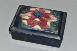 A MOORCROFT POTTERY RECTANGULAR TRINKET BOX AND COVER DECORATED IN A PINK ANEMONE PATTERN, on a dark