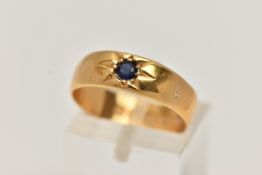 A 22CT GOLD BAND RING, set with a circular cut blue sapphire in a star setting, approximate band