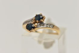 AN 18CT GOLD SAPPHIRE AND DIAMOND RING, cross over design, set with two oval cut blue sapphires, and