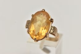 A CITRINE DRESS RING, a large oval cut citrine, prong set in yellow metal, textured raised