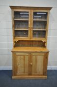 A PINE DRESSER, the top with two glazed doors, enclosing three shelves, the base with two