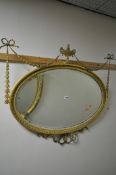 A 19TH CENTURY GILT GESSO OVAL WALL MIRROR, with ribbon and swag detail, surrounding an urn, and a