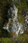A DISTRESSED SECTION OF A GARDEN ORNAMENT OF A BUDDHA, that appears to be wearing a crown and
