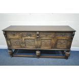 A CARVED OAK SIDEBOARD, with four drawers and cupboard doors, on acorn supports united by