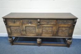 A CARVED OAK SIDEBOARD, with four drawers and cupboard doors, on acorn supports united by