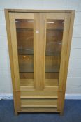 A MARKS AND SPENCER LIGHT OAK GLAZED TWO DOOR ILLUMINATED DISPLAY CABINET, with two drawers, width