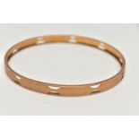 AN EARLY 20TH CENTURY ARM CUFF, a rose gold bangle decorated with an engine turned pattern and