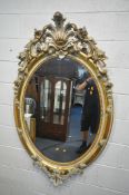A LARGE 19TH CENTURY OVAL GILTWOOD WALL MIRROR, with a scrolled foliate design, and bevelled