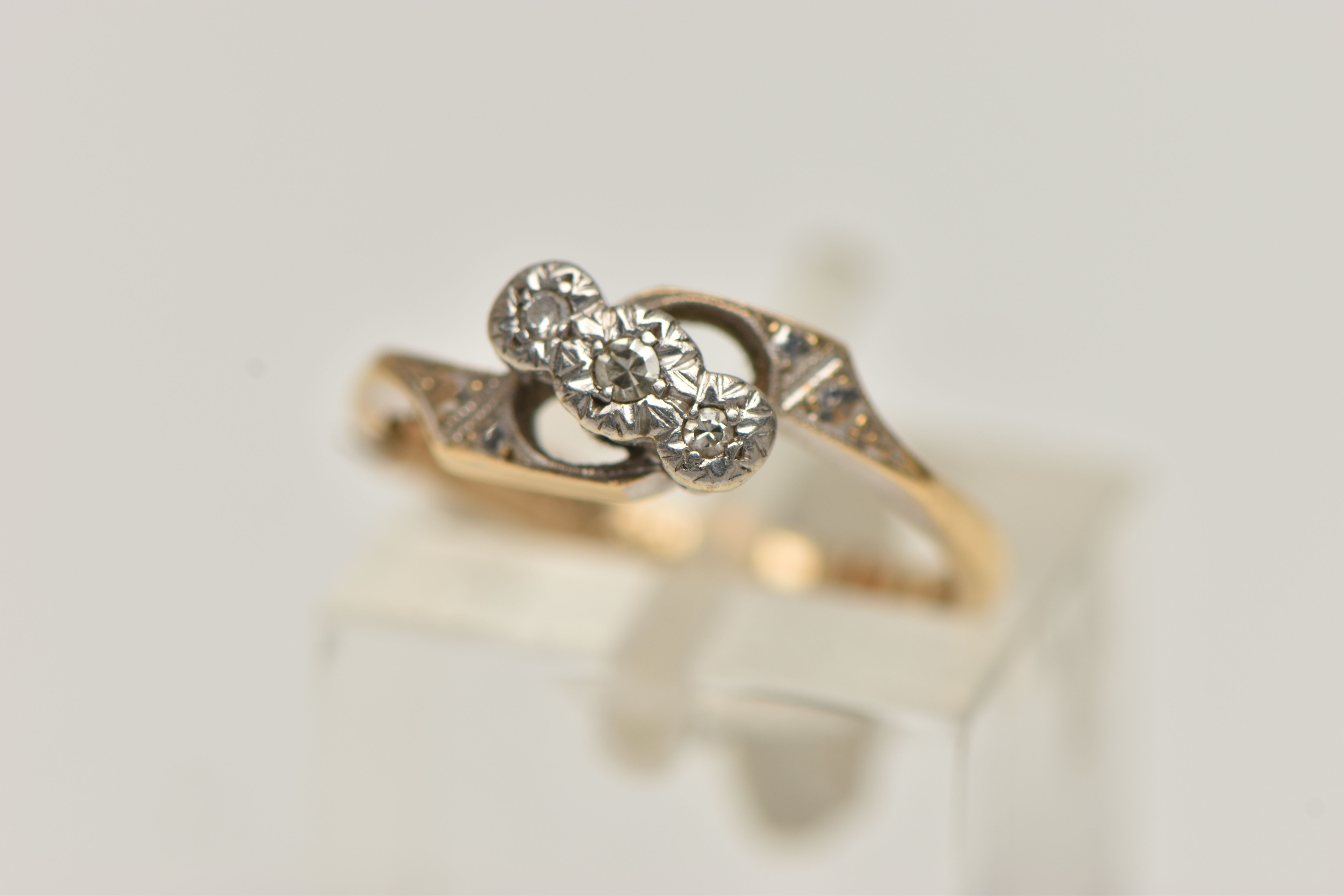 A THREE STONE DIAMOND RING, a yellow and white metal three stone diamond ring, three small single