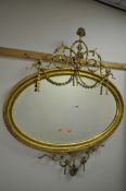 A 19TH CENTURY GILT GESSO OVAL WALL MIRROR, the frame with scrolled swag and ribbon decoration, on a