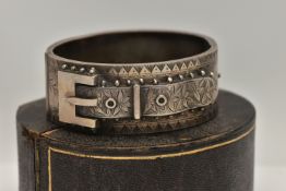 A LATE VICTORIAN SILVER HINGED BANGLE, of a belt and buckle design, floral detail with applied