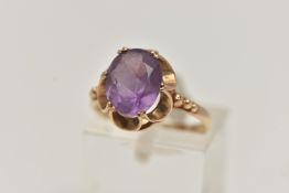 A 9CT GOLD AMETHYST RING, an oval cut amethyst prong set in a yellow gold scalloped mount,