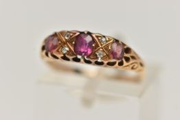 A YELLOW METAL GEM SET RING, a centrally set oval cut ruby, four old cut diamonds, two oval cut pink