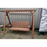 A TEAK SLATTED GARDEN SWING, with a top for a canopy, length 214cm x depth 127cm x height 176cm (