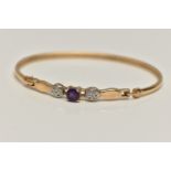 A 9CT GOLD GEM SET BANGLE, set with a central circular cut amethyst, flanked with single cut diamond