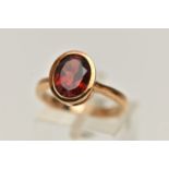 A 9CT GOLD GARNET RING, oval cut garnet in a collet setting, mount measuring approximately length