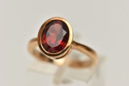 A 9CT GOLD GARNET RING, oval cut garnet in a collet setting, mount measuring approximately length