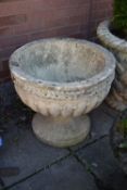 A WEATHERED CIRCULAR COMPOSITE GARDEN URN, on a seperate plinth base, diamater 54cm x height 47cm (