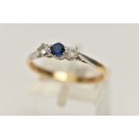 A YELLOW METAL THREE STONE RING, set with a central circular cut blue sapphire, flanked with