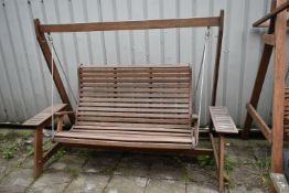 A TEAK GARDEN SWING, with platforms at each end for storage, length 226cm x depth 117cm x height
