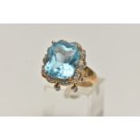 A 9CT GOLD TOPAZ AND DIAMOND DRESS RING, centring on a large cushion cut blue topaz, measuring