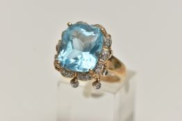 A 9CT GOLD TOPAZ AND DIAMOND DRESS RING, centring on a large cushion cut blue topaz, measuring