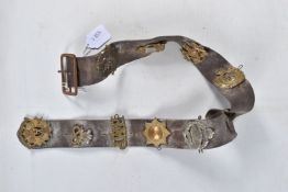 A LEATHER BELT WITH VARIOUS CAP BADGES AND SHOULDER TITLES ATTATCHED, there are twelves badges