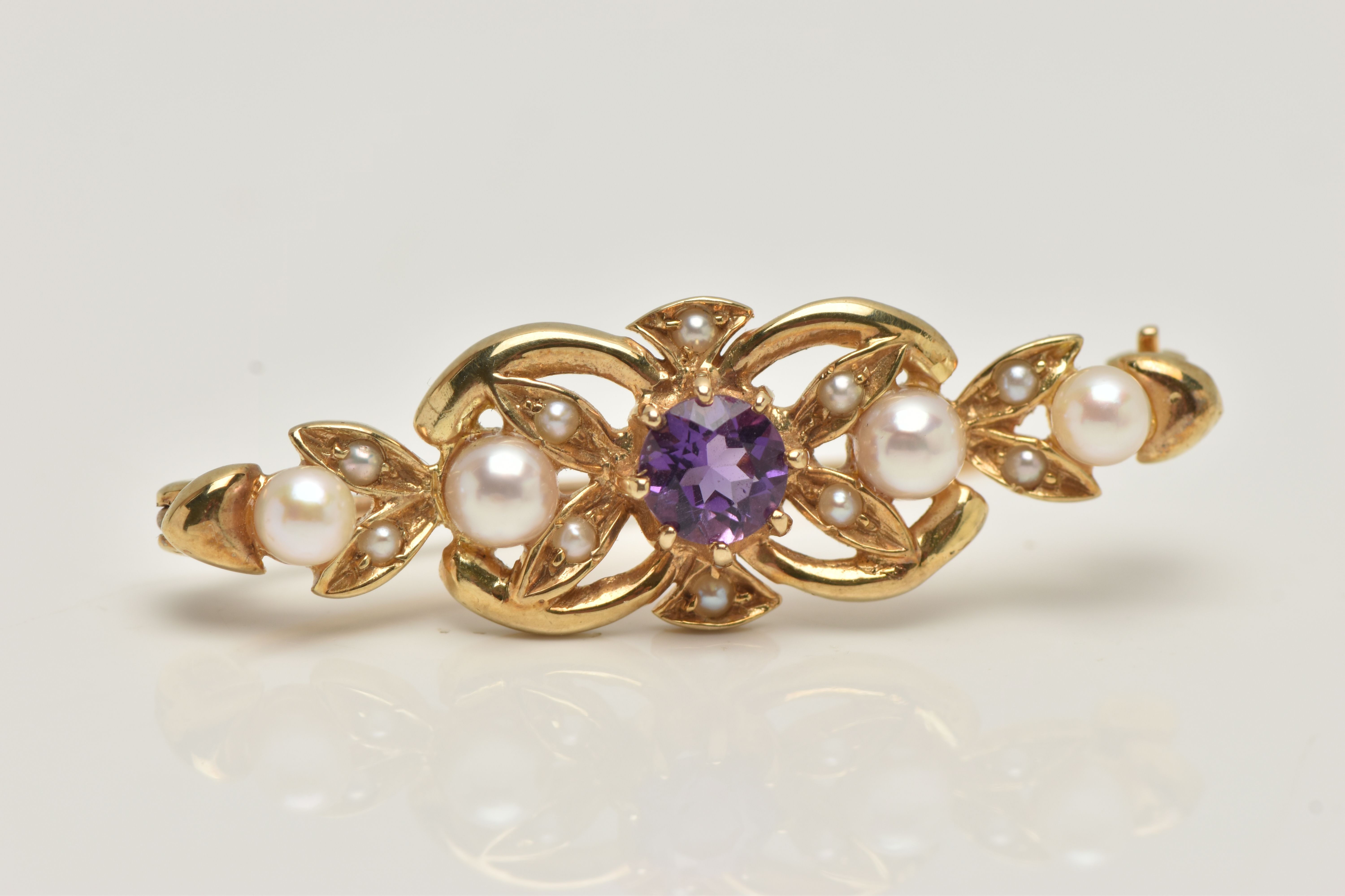 A 9CT GOLD AMETHYST AND SEED PEARL BROOCH, open work brooch set with a central circular cut