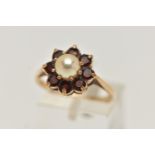 A YELLOW METAL PEARL AND GARNET CLUSTER RING, centring on a single cultured pearl claw set within