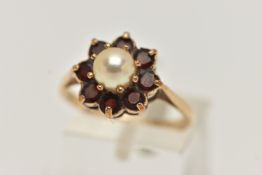 A YELLOW METAL PEARL AND GARNET CLUSTER RING, centring on a single cultured pearl claw set within