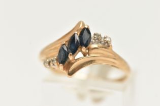 A YELLOW METAL GEM SET RING, asymmetrical design set with three marquise cut blue sapphires, and