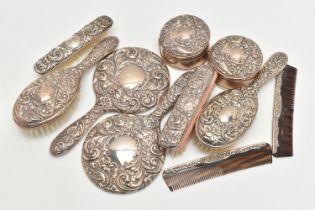 TWO ELIZABETH II SILVER MOUNTED FIVE PIECE DRESSING TABLE SETS, both repoussé decorated with foliate