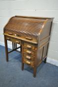 AN EARLY TO MID 20TH CENTURY OAK ROLL TOP DESK, enclosing an arrangement of pigeon holes, over