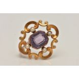 A YELLOW METAL AMETHYST AND SEED PEARL BROOCH, open work scrolling brooch set with a central emerald