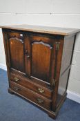 A REPRODUCTION PANELLED OAK TWO DOOR CABINET, with two drawers, width 95cm x depth 51cm x height