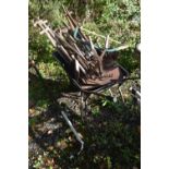 A WHEELBARROW CONTAINING VARIOUS GARDEN TOOLS, to include rakes, shovels, pitch forks, etc (