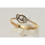 A YELLOW METAL THREE STONE DIAMOND RING, of a cross over design, set with a central round