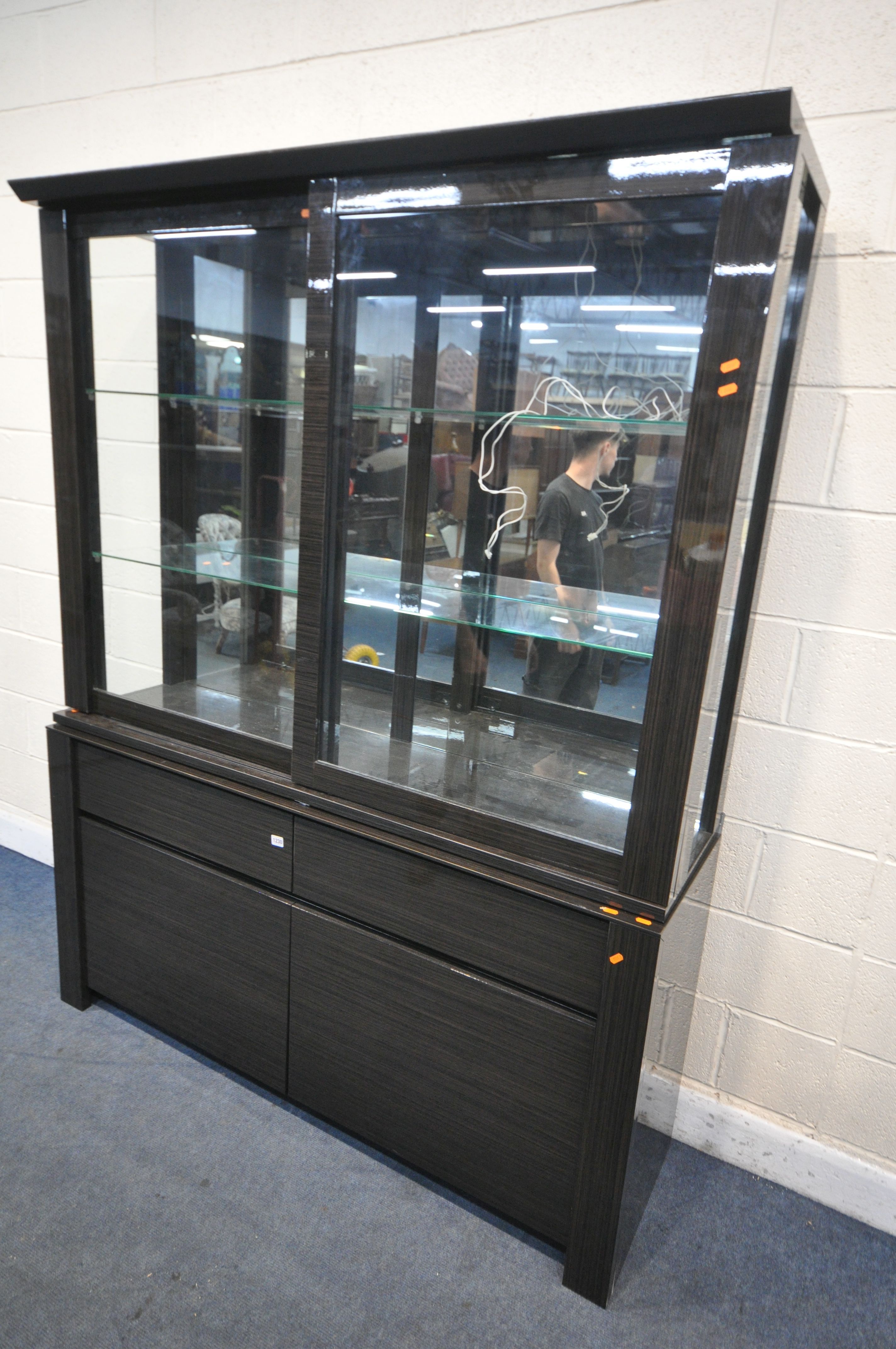 A BLACK FINISH GLAZED DISPLAY CABINET, with sliding doors, enclosing two glass shelves, over a