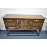 AN OAK LINENFOLD SIDEBOARD, with cupboard doors flanking two drawers, on turned supports united by a