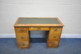 AN OAK KNEE HOLE DESK, with a green leatherette writing surface, with seven drawers, length 109cm
