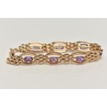 A 9CT GOLD AMETHYST BRACELET, seven oval cut amethyst prong set in yellow gold, interspaced