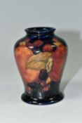 A SMALL MOORCROFT POTTERY 'POMEGRANATE' BALUSTER VASE, with tube lined Pomegranate pattern on a navy