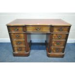 A CHARLES BARR MAHOGANY KNEE HOLE DESK, with a red leather writing surface, and nine drawers,